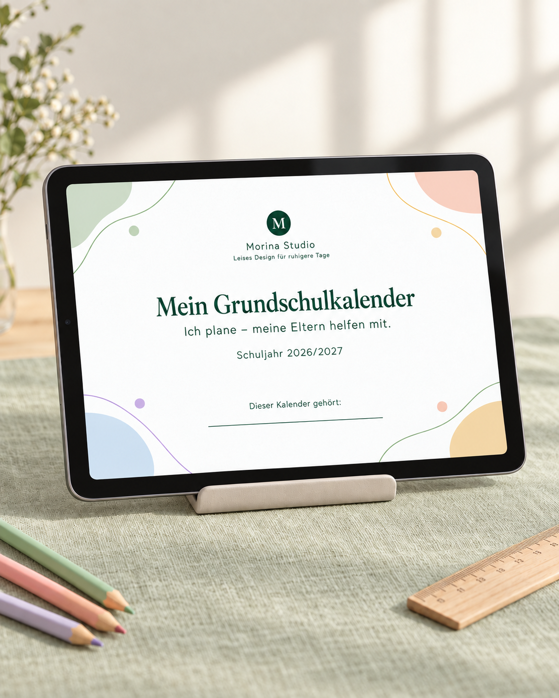 Der Grundschulkalender auf einem iPad auf einem hellen Tisch mit Lineal und Buntstiften